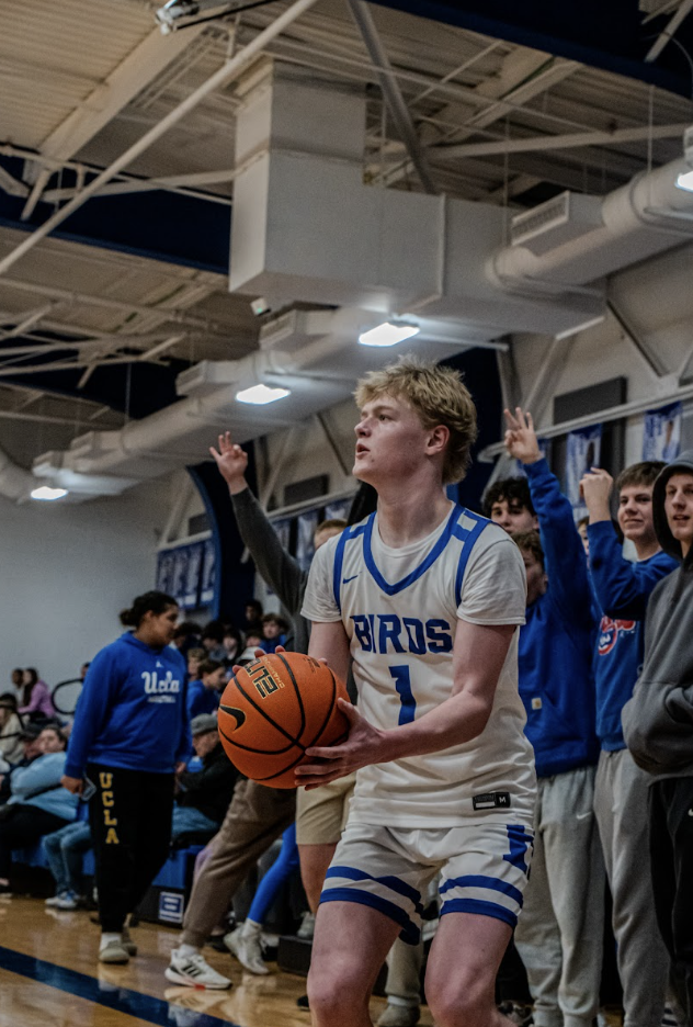 Finn Bouldin (11) shoots a three as the O-ZONE cheers behind him. “Energy in the gym improves my performance and I feel like I play better with good energy,” Bouldin said. 